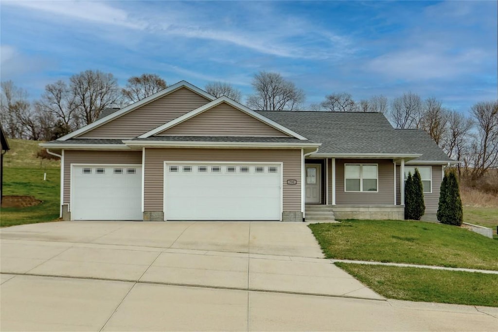 view of front of property featuring a shingled roof, driveway, an attached garage, and a front lawn