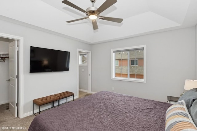 bedroom featuring light carpet, a walk in closet, a closet, and a raised ceiling