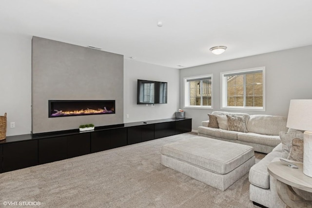 carpeted living area featuring a lit fireplace