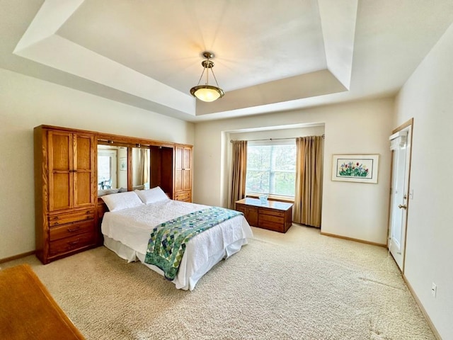 bedroom with baseboards, a raised ceiling, and light colored carpet