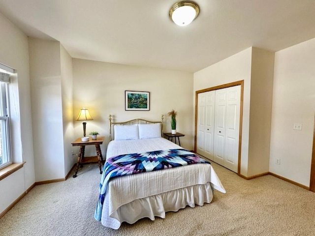 carpeted bedroom with a closet and baseboards