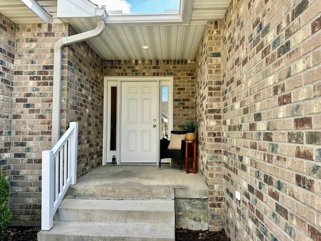 view of exterior entry with a porch and brick siding
