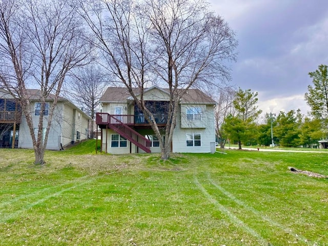 rear view of house featuring stairway, a deck, and a lawn