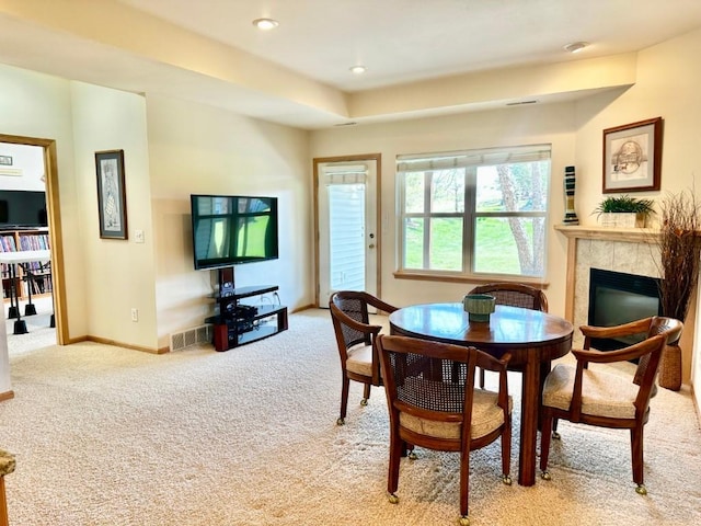 dining space with light carpet, a fireplace, and baseboards