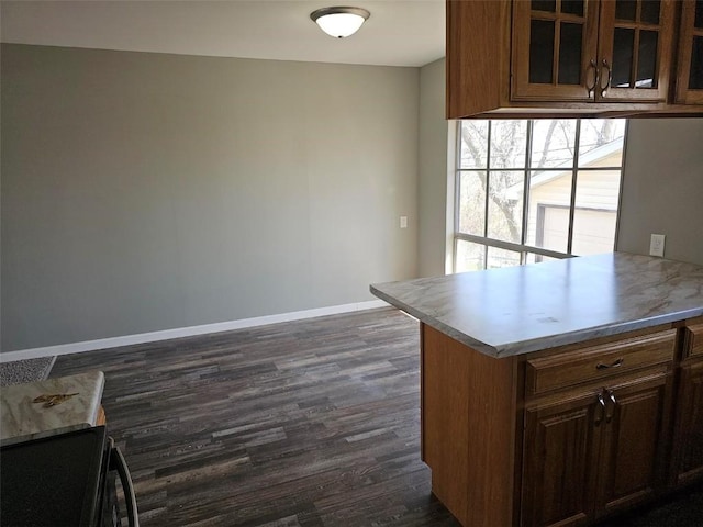 1025 Pawnee Dr NW, Cedar Rapids, IA 52405 - kitchen with baseboards, dark wood-type flooring, glass insert cabinets, light countertops, and a peninsula