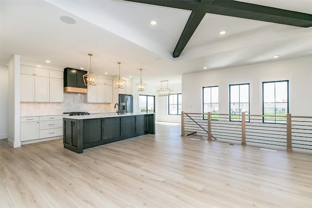 kitchen with stainless steel fridge, white cabinets, light countertops, custom exhaust hood, and recessed lighting