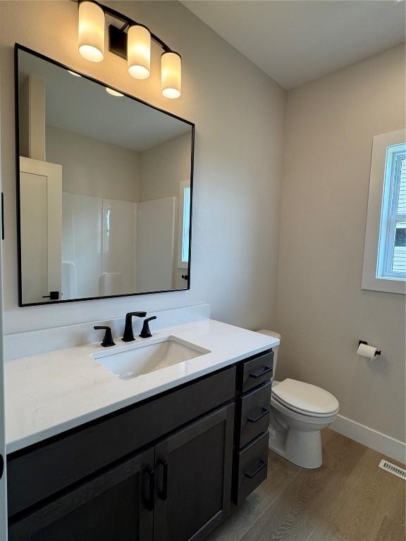 4018 Peridot Dr, Marion, IA 52302 - bathroom featuring wood finished floors, vanity, toilet, baseboards, and a shower