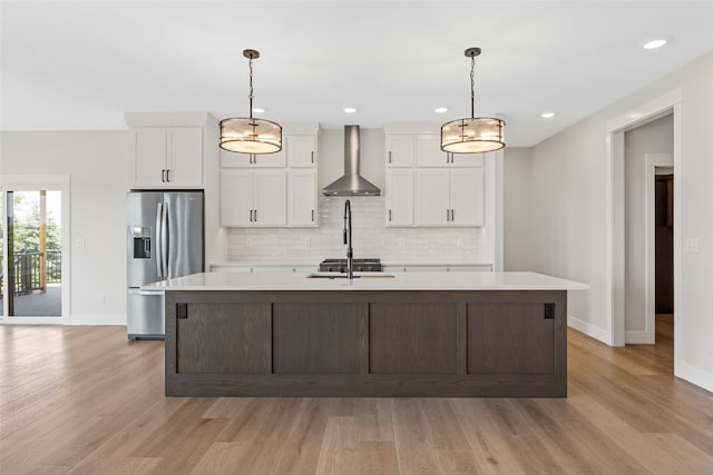 4018 Peridot Dr, Marion, IA 52302 - kitchen featuring wall chimney exhaust hood, stainless steel fridge, a center island with sink, light countertops, and light wood-style flooring