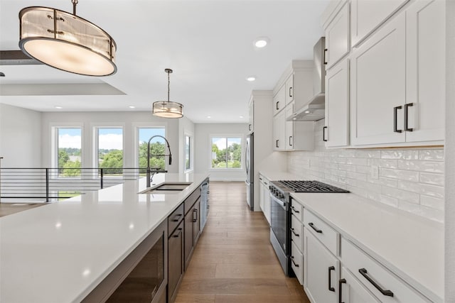 4018 Peridot Dr, Marion, IA 52302 - kitchen with appliances with stainless steel finishes, wall chimney exhaust hood, wood finished floors, light countertops, and white cabinets