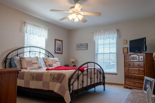 bedroom featuring baseboards, multiple windows, carpet flooring, and a ceiling fan