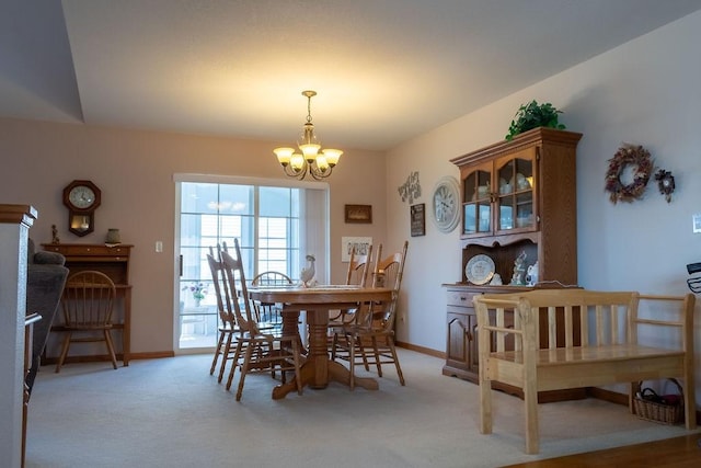 dining area featuring a chandelier, light colored carpet, and baseboards