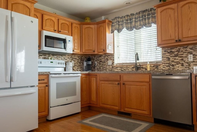 kitchen featuring tasteful backsplash, white appliances, and light wood finished floors