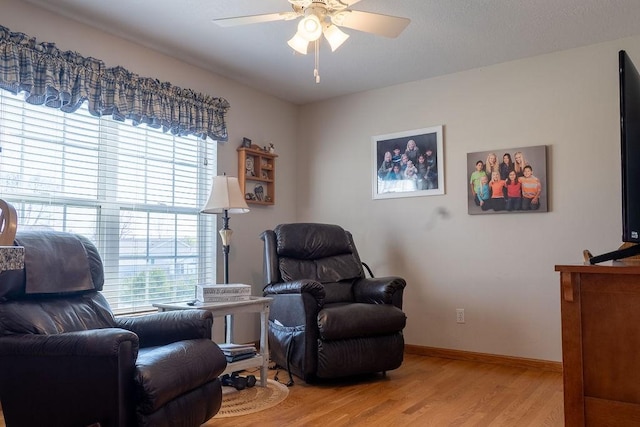 sitting room with baseboards, a ceiling fan, and wood finished floors