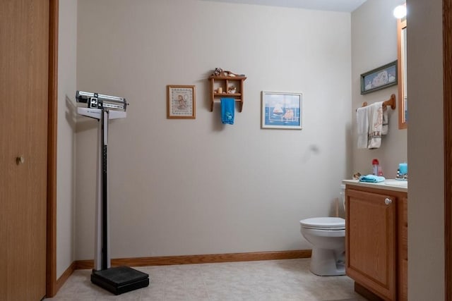 half bathroom with vanity, baseboards, and toilet
