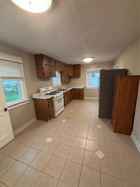 832 Daniels St NE, Cedar Rapids, IA 52402 - kitchen with gas range gas stove, baseboards, light countertops, plenty of natural light, and a textured ceiling
