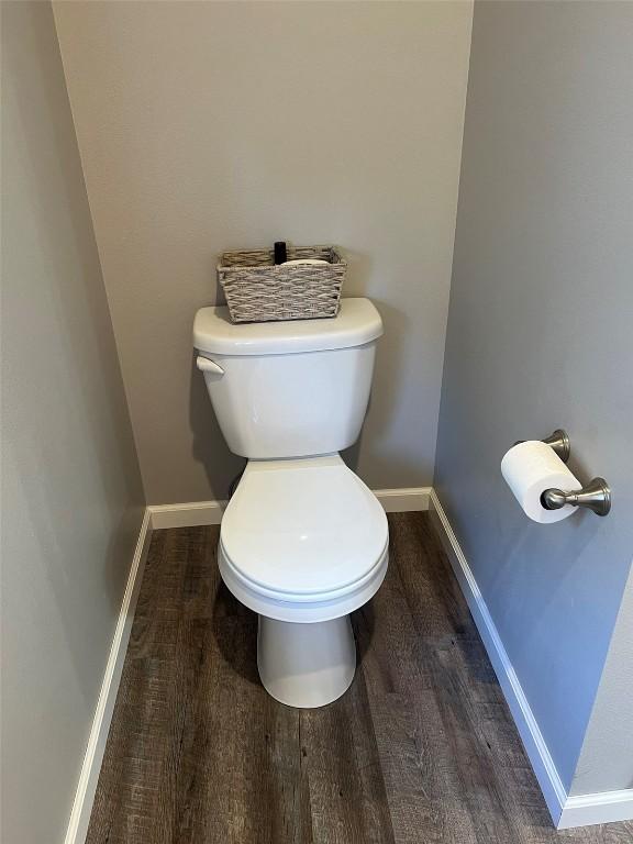 bathroom with toilet, wood finished floors, and baseboards