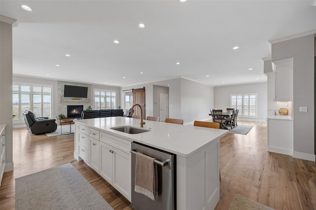 kitchen with a sink, open floor plan, a kitchen island with sink, a healthy amount of sunlight, and a large fireplace