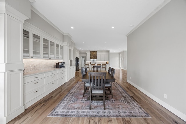 dining space with baseboards, recessed lighting, crown molding, decorative columns, and light wood finished floors