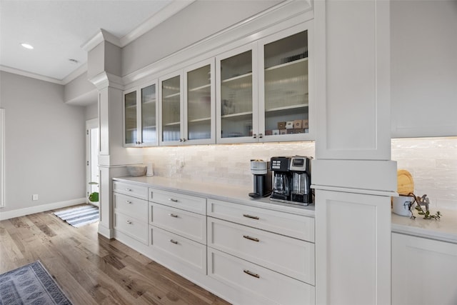 bar featuring wood finished floors, baseboards, ornamental molding, and decorative backsplash