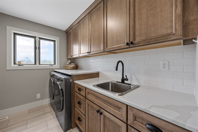 laundry area with baseboards, a sink, cabinet space, and washing machine and dryer