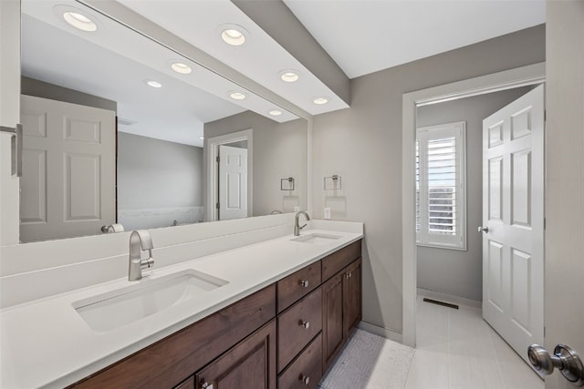bathroom with double vanity, a sink, baseboards, and recessed lighting