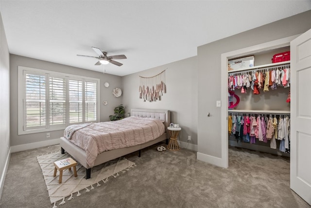 carpeted bedroom with a closet, baseboards, a ceiling fan, and a walk in closet