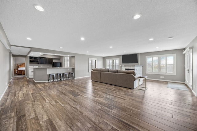 living area featuring recessed lighting, a textured ceiling, baseboards, and dark wood finished floors