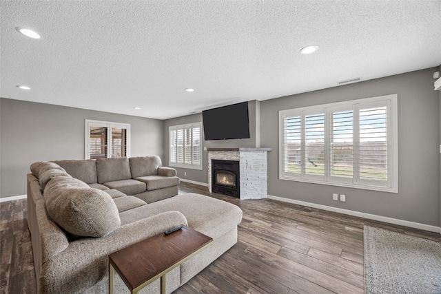 living room featuring visible vents, a stone fireplace, and a textured ceiling
