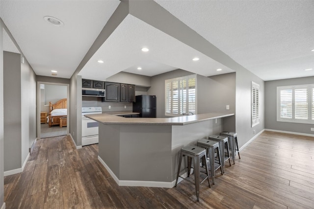 kitchen featuring range hood, freestanding refrigerator, white range with electric stovetop, and dark wood-style flooring