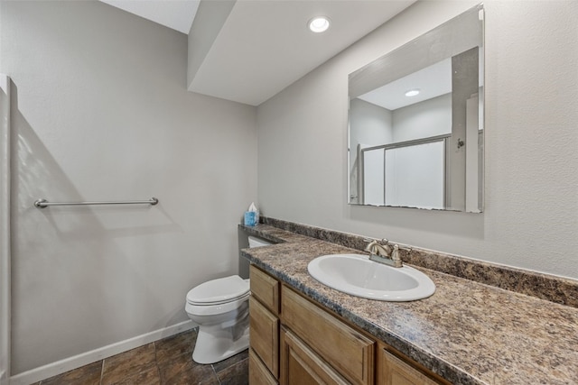bathroom with toilet, a stall shower, vanity, and baseboards