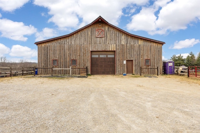 view of barn featuring driveway and fence