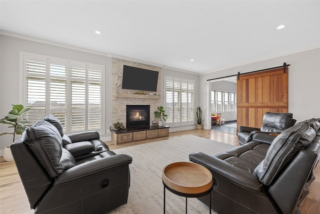 living area with recessed lighting, light wood-style floors, a stone fireplace, and crown molding