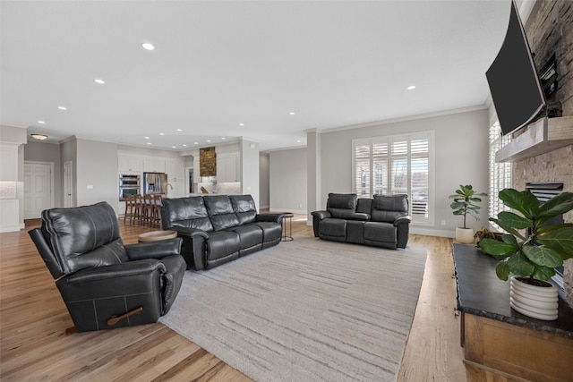 living area with crown molding, light wood-style floors, a fireplace, and recessed lighting