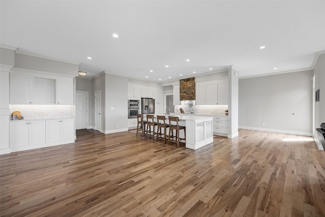 living area with recessed lighting, light wood-style flooring, and ornamental molding