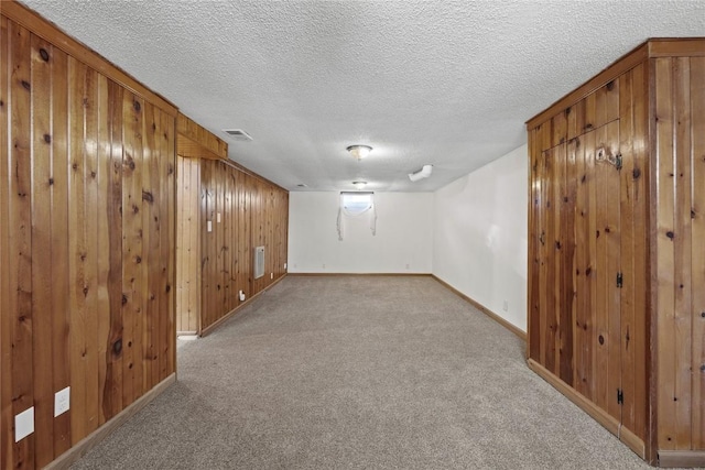 finished below grade area with a textured ceiling, carpet floors, and baseboards