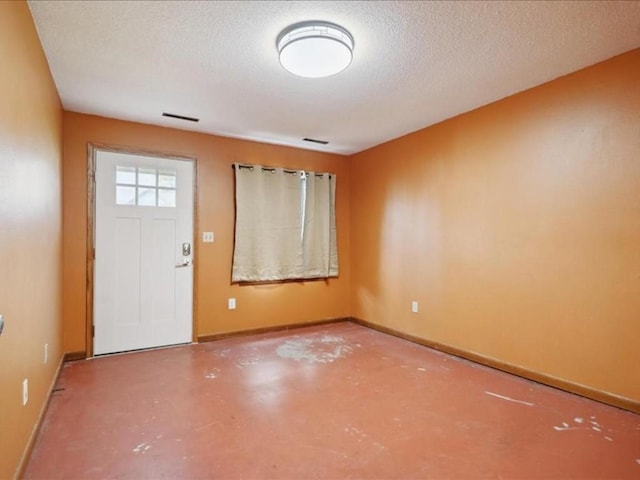 entrance foyer featuring concrete flooring, visible vents, baseboards, and a textured ceiling