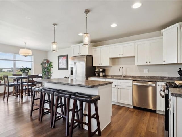kitchen featuring dark countertops, a sink, white cabinets, and stainless steel appliances