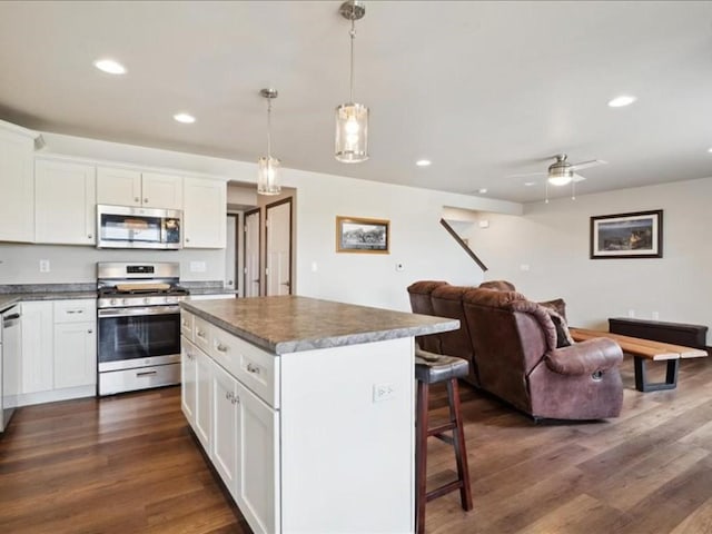 kitchen featuring a kitchen breakfast bar, dark wood-type flooring, a center island, appliances with stainless steel finishes, and open floor plan