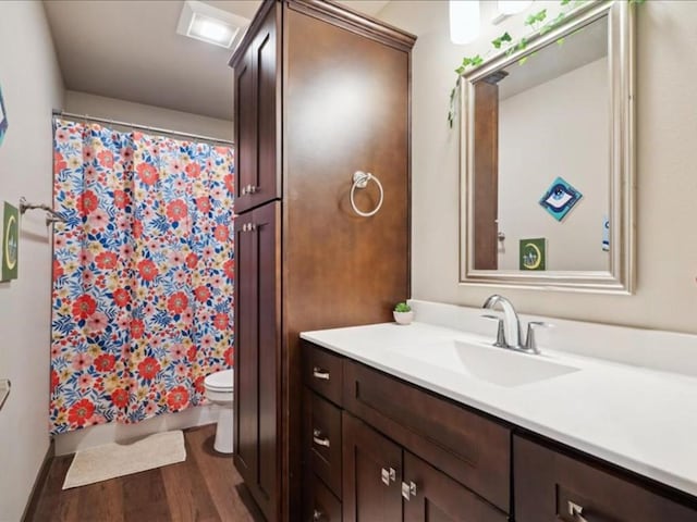 full bath featuring toilet, a shower with shower curtain, vanity, and wood finished floors