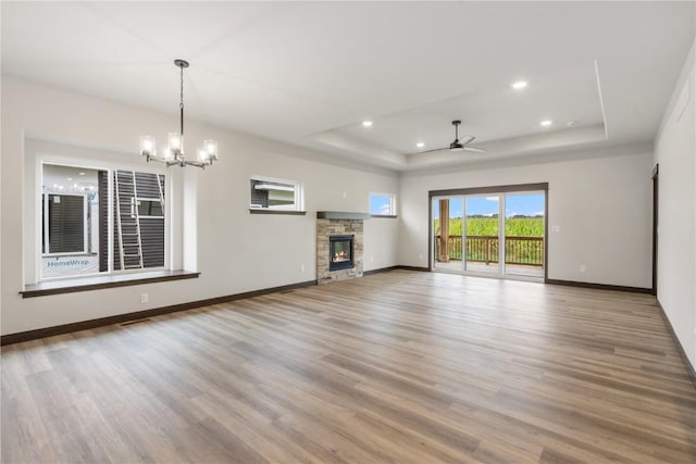 1232 Berkshire Ln, North Liberty, IA 52317 - unfurnished living room featuring a raised ceiling, wood finished floors, ceiling fan, a stone fireplace, and a chandelier