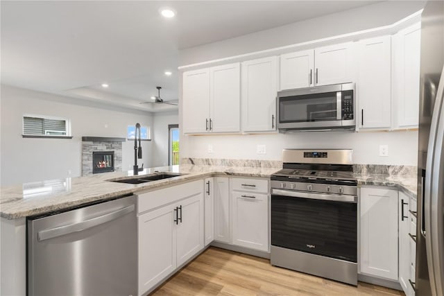 1232 Berkshire Ln, North Liberty, IA 52317 - kitchen with appliances with stainless steel finishes, a sink, a peninsula, a ceiling fan, and white cabinets