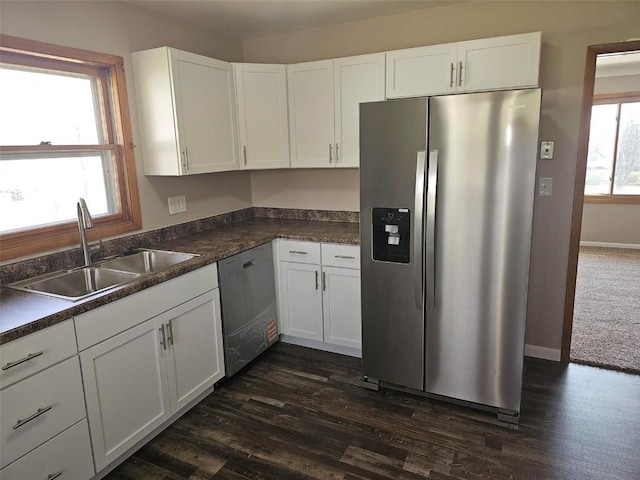 2704 Otis Rd SE, Cedar Rapids, IA 52403 - kitchen with appliances with stainless steel finishes, a sink, white cabinetry, dark countertops, and dark wood-type flooring