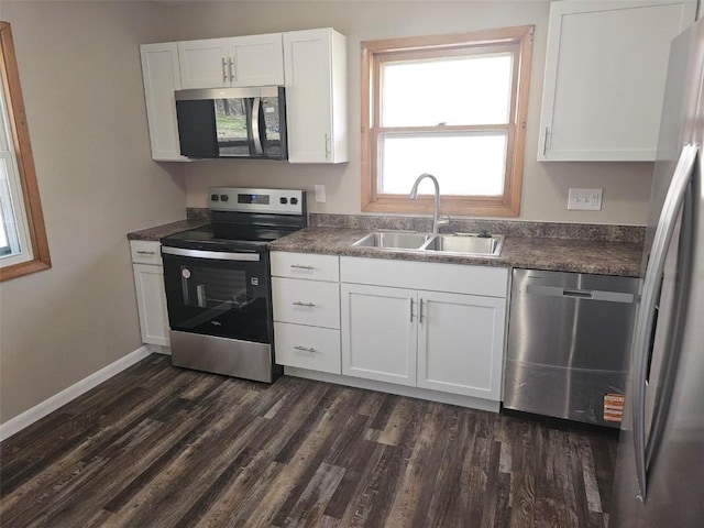 2704 Otis Rd SE, Cedar Rapids, IA 52403 - kitchen with appliances with stainless steel finishes, a sink, dark countertops, dark wood-type flooring, and white cabinets