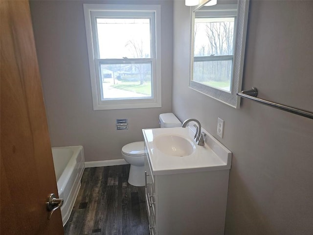 2704 Otis Rd SE, Cedar Rapids, IA 52403 - full bathroom with toilet, vanity, a bathtub, wood finished floors, and baseboards