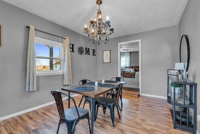 dining space with light wood finished floors, baseboards, and an inviting chandelier