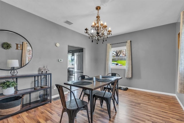 dining area featuring wood finished floors, an inviting chandelier, baseboards, and a wealth of natural light