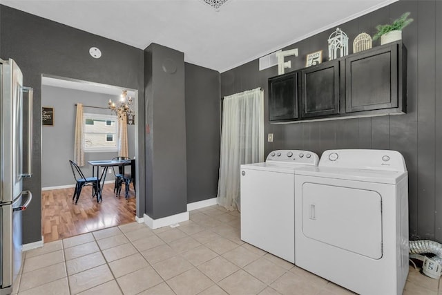 washroom featuring light tile patterned floors, baseboards, an inviting chandelier, separate washer and dryer, and cabinet space