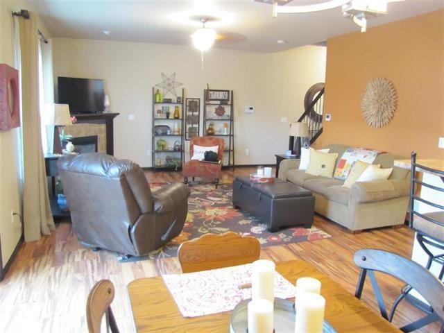 1785 Sara Ct, North Liberty, IA 52317 - living room featuring stairway, a tile fireplace, wood finished floors, and a ceiling fan