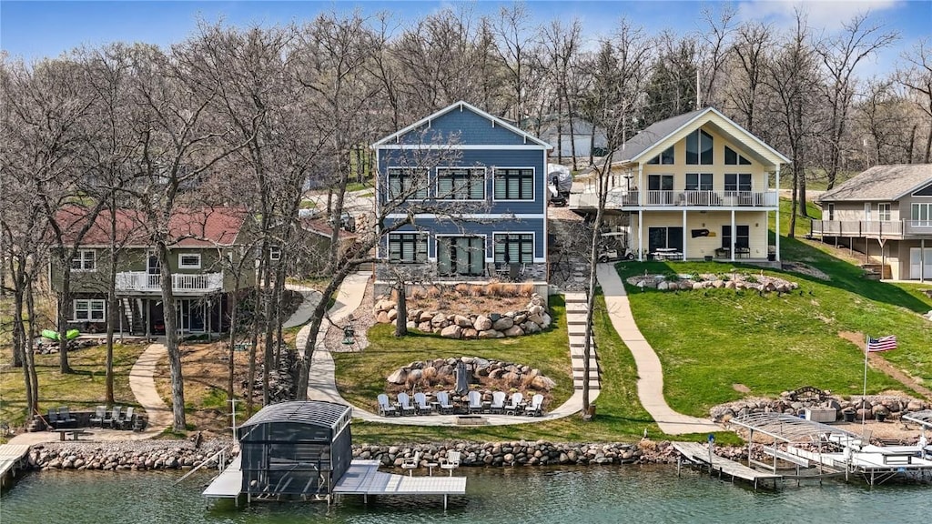 back of house featuring a yard, a water view, and a balcony