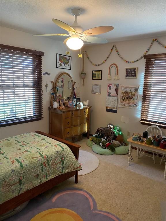 carpeted bedroom with a ceiling fan and a textured ceiling